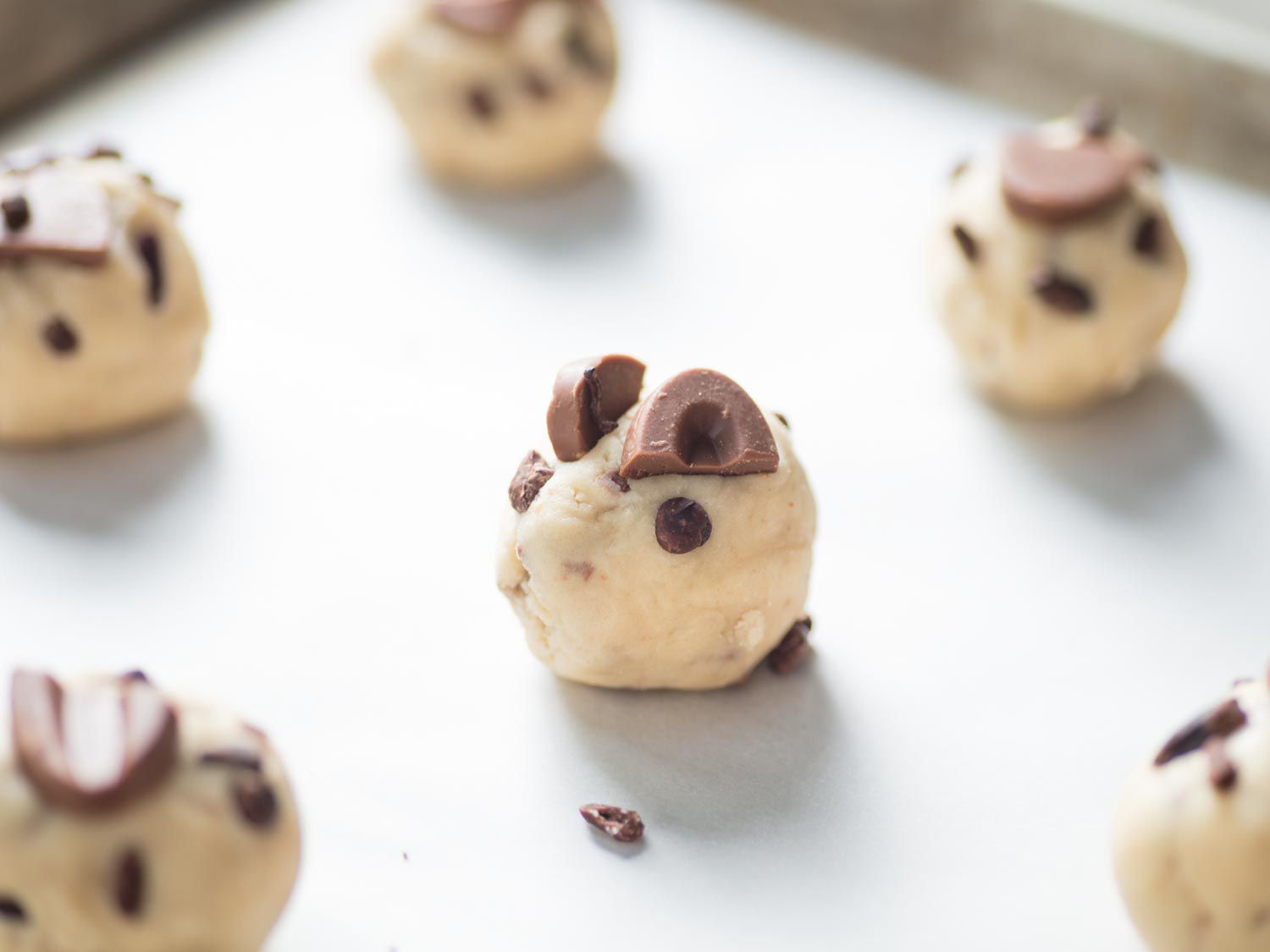 Balls of cocoa butter cookie dough topped with chunks of milk chocolate.
