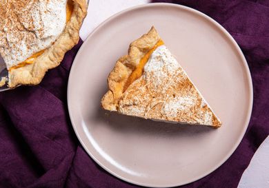 Slice of pumpkin chiffon pie on a serving plate next to pie plate with pumpkin chiffon pie