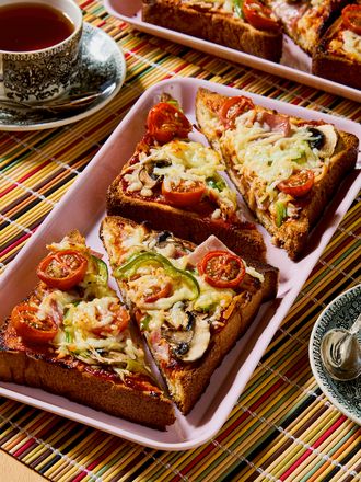 Slices of pizza toast arranged on a tray with cups of tea