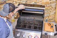 A hand opening the hood of the Weber Spirit EP-435 Gas Grill