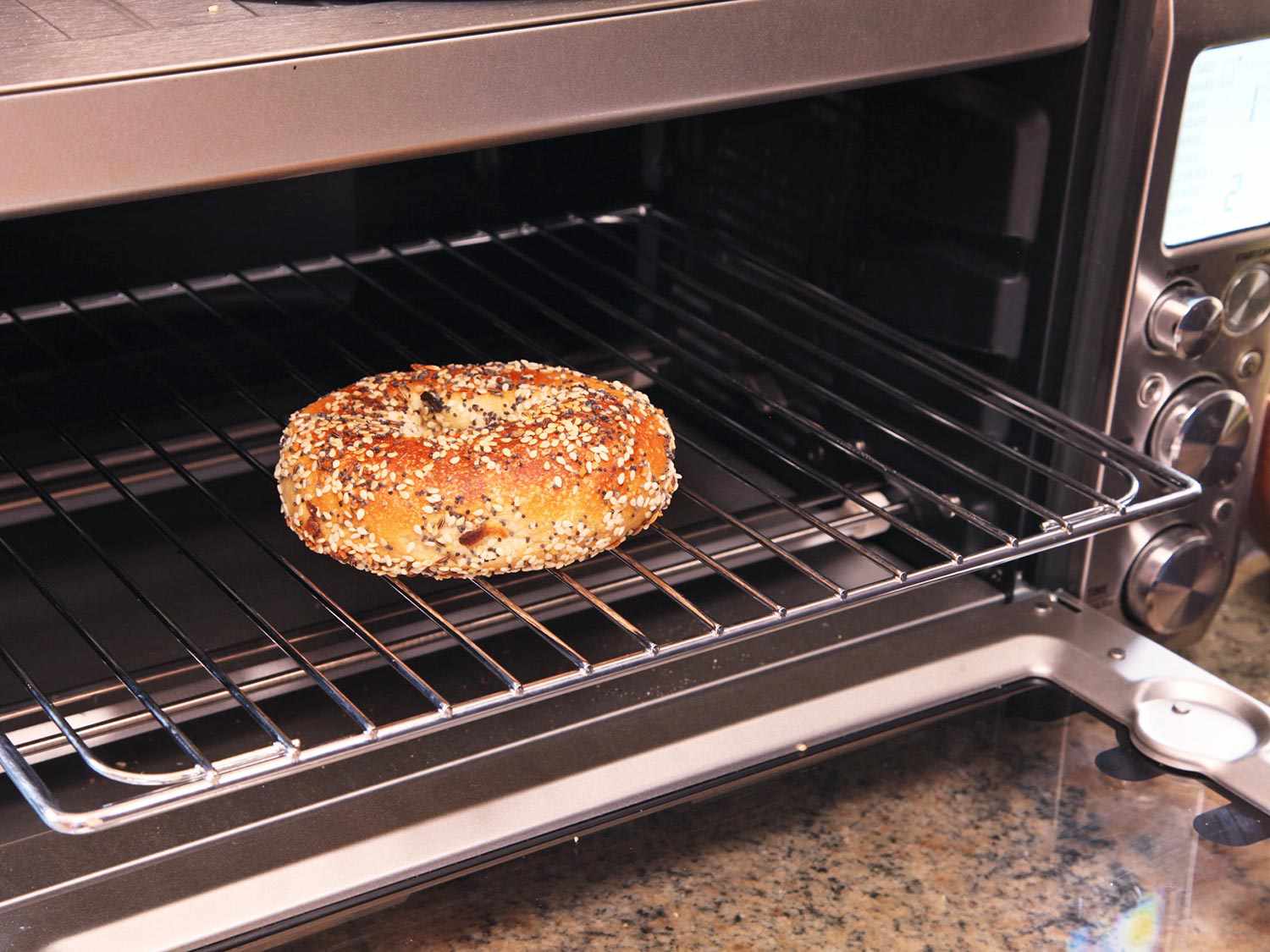 A bagel resting on a rack in an oven.