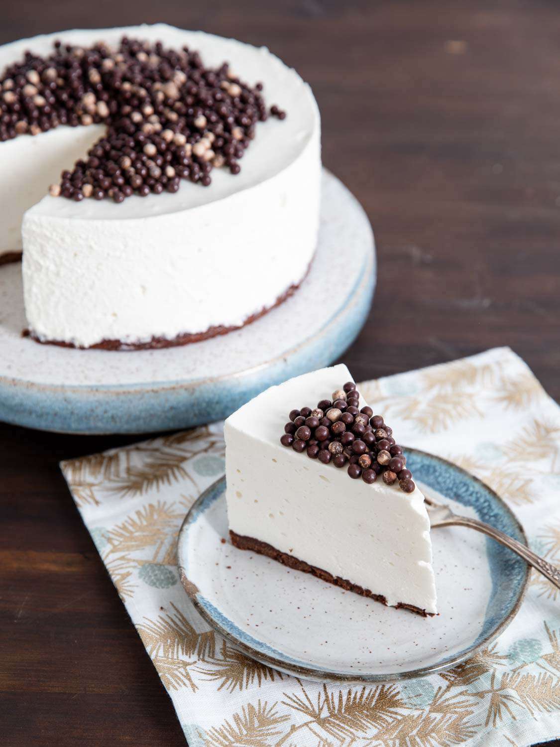A slice of fluffy and white no-bake cheesecake topped with chocolate pearls.
