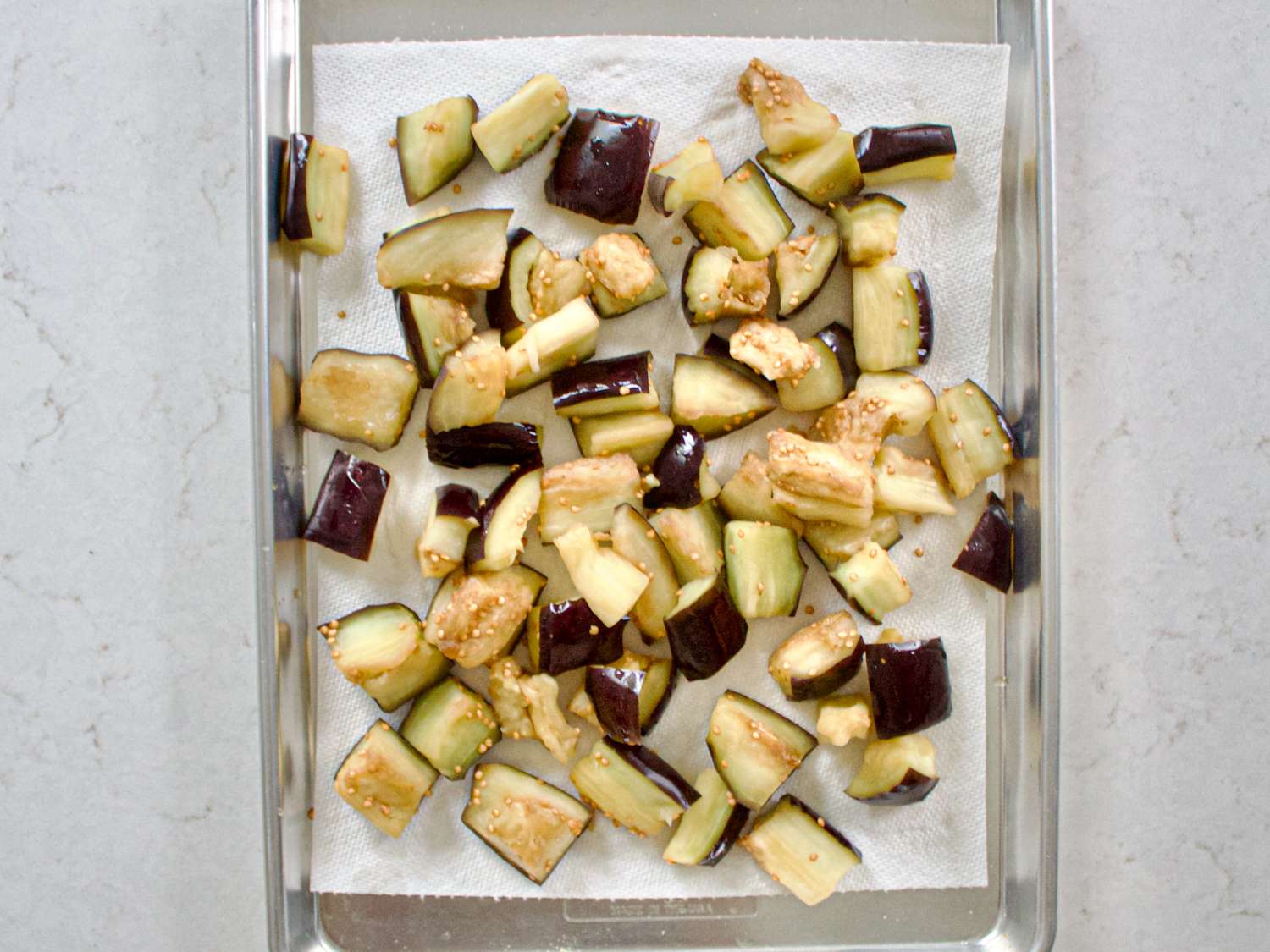 Diced eggplant pieces arranged on a lined baking tray prepared for cooking