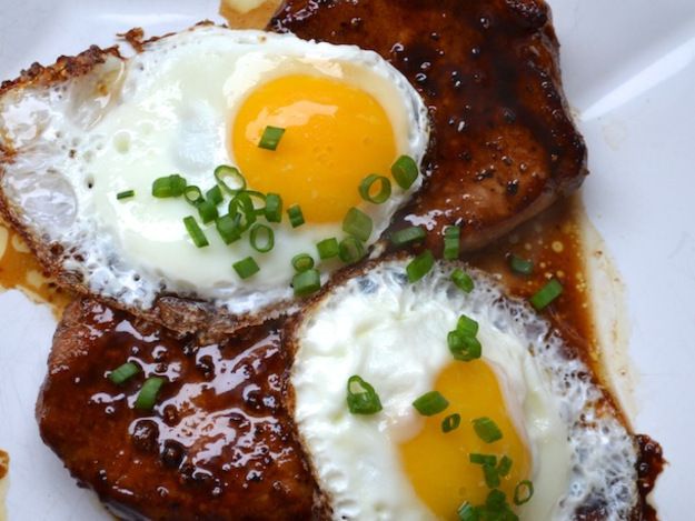 Bourbon Glazed Pork Chops with two fried eggs, and sliced chives on top. 