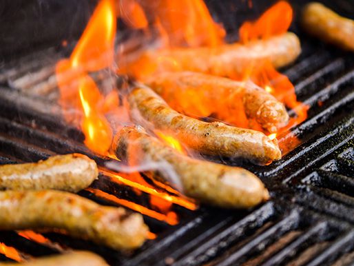 Merguez sausages on a grill with flames.