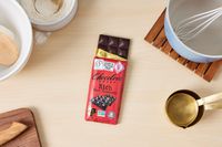 A partially unwrapped dark chocolate bar on a kitchen countertop.