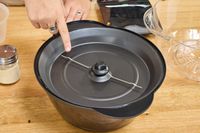 A person points to the bottom of the West Bend Stir Crazy Electric Hot Oil Popcorn Popper