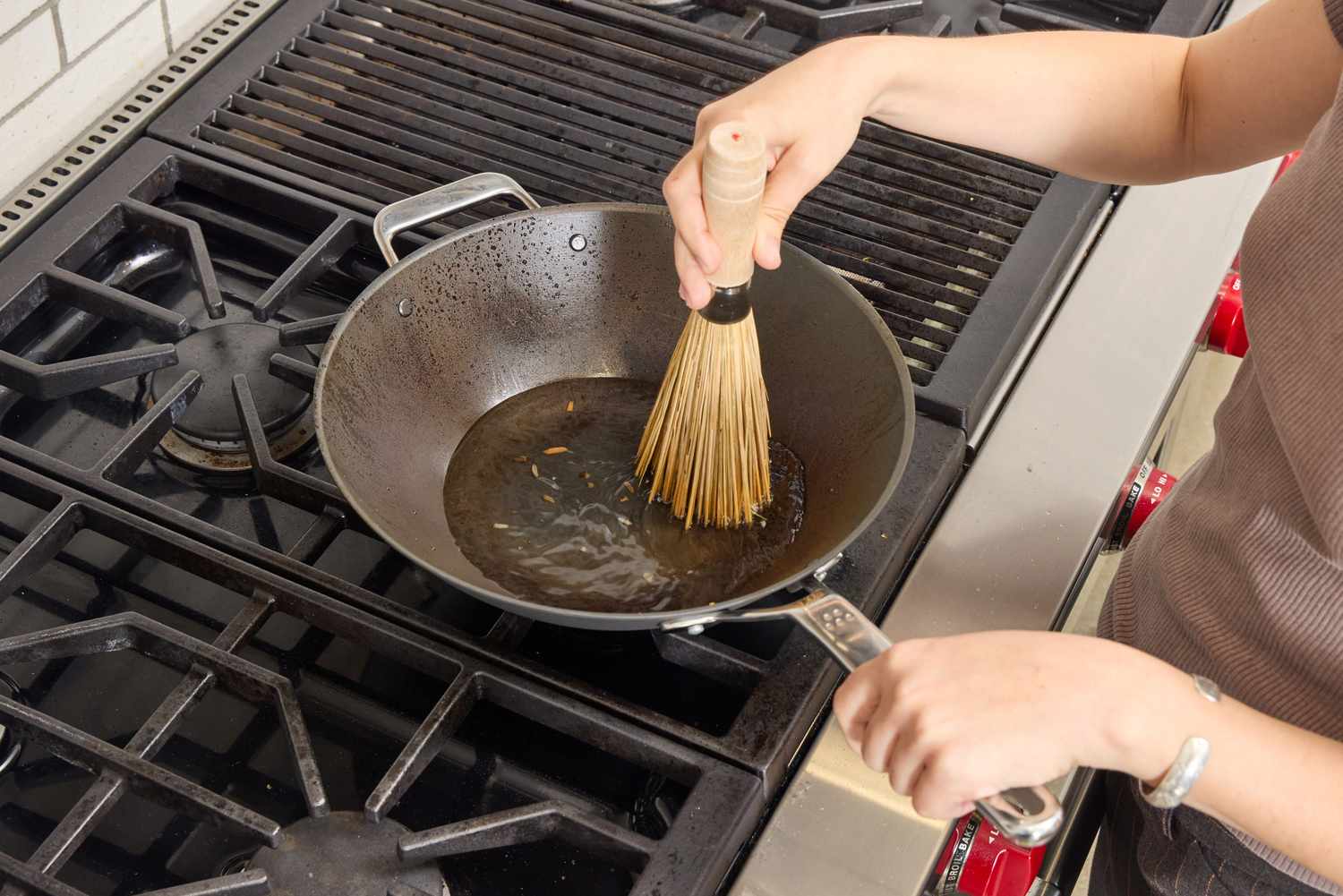 A person oils the bottom of the Misen 12 Inch Carbon Steel Wok