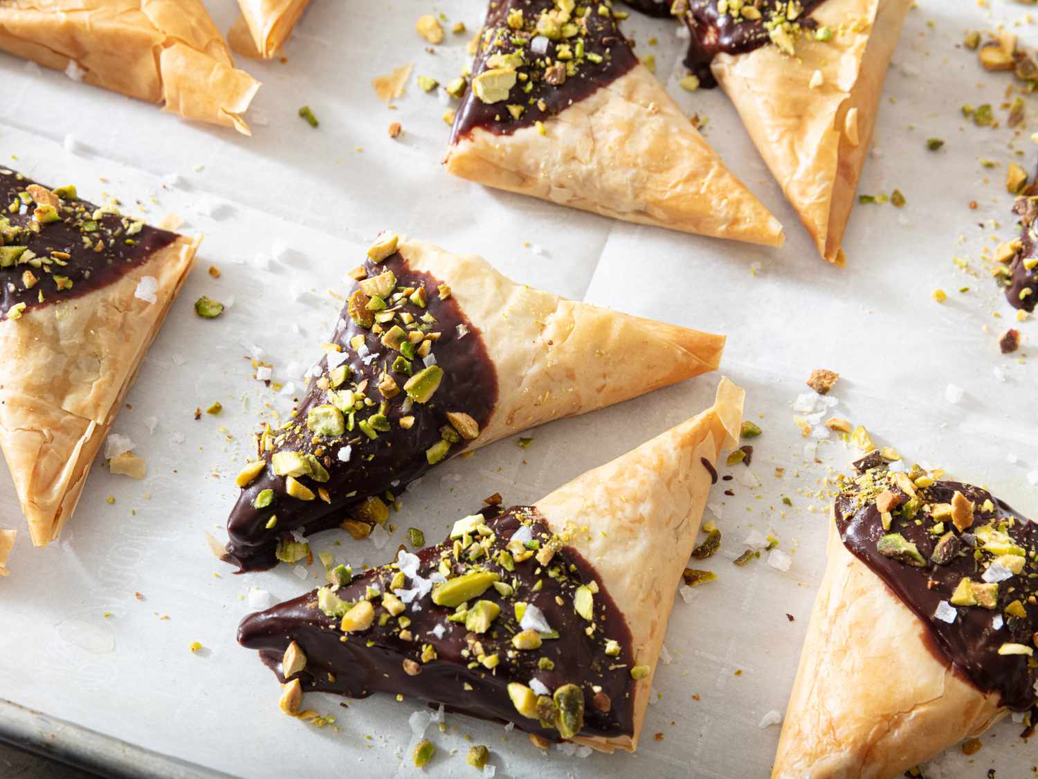 Dubai chocolate triangles arranged on sheetpan topped with pistachio