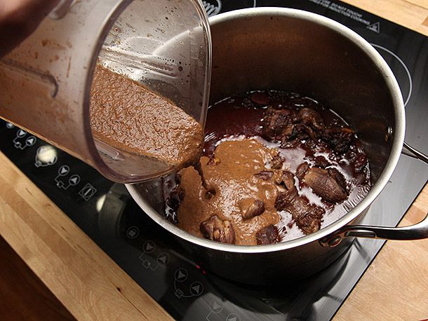 Pouring pureed soup mixture into the pot of remaining black bean soup to thicken.