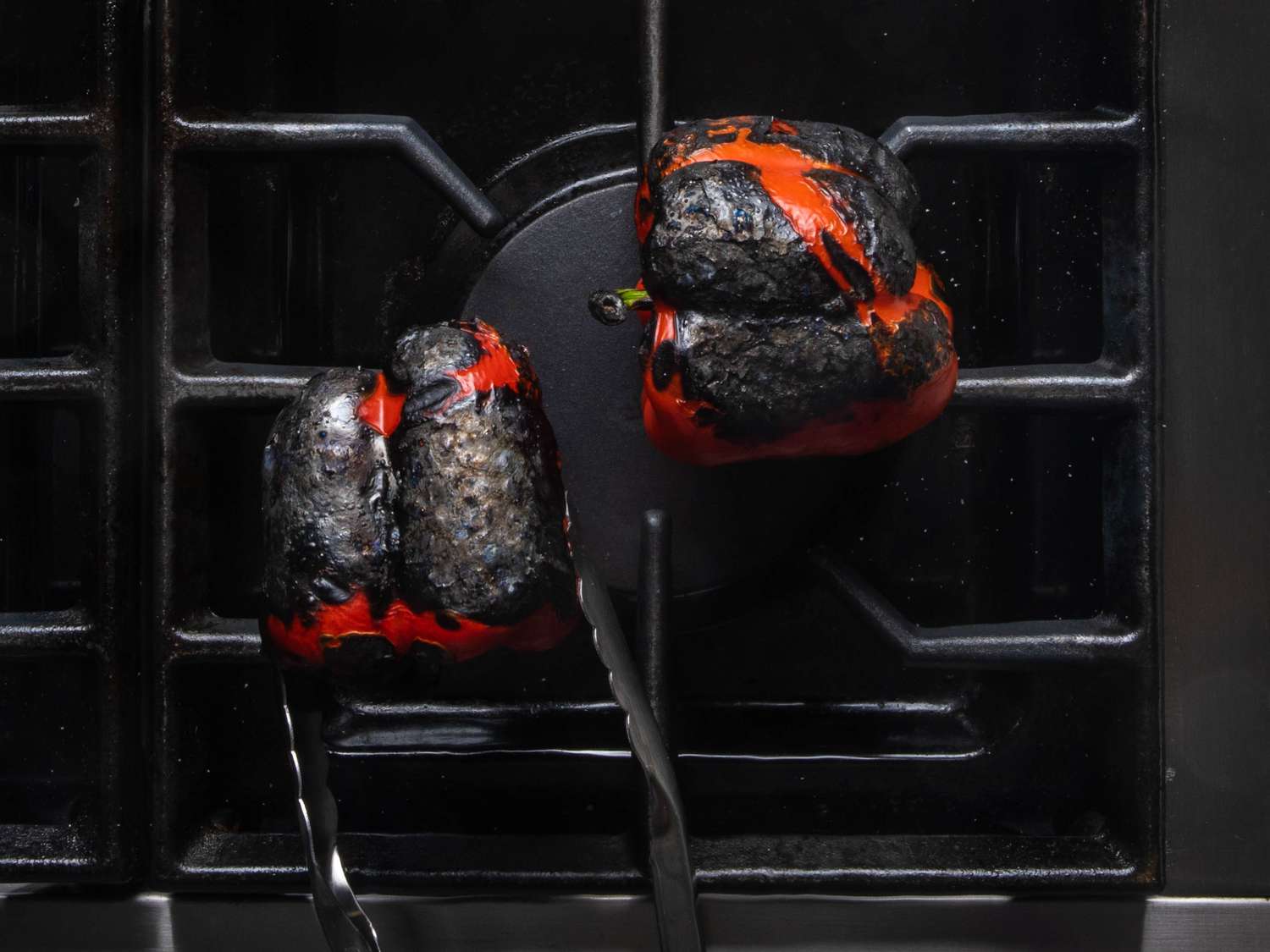 Charred red bell peppers sitting directly over the burner flame.