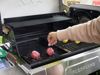 a person salting burgers on a griddle
