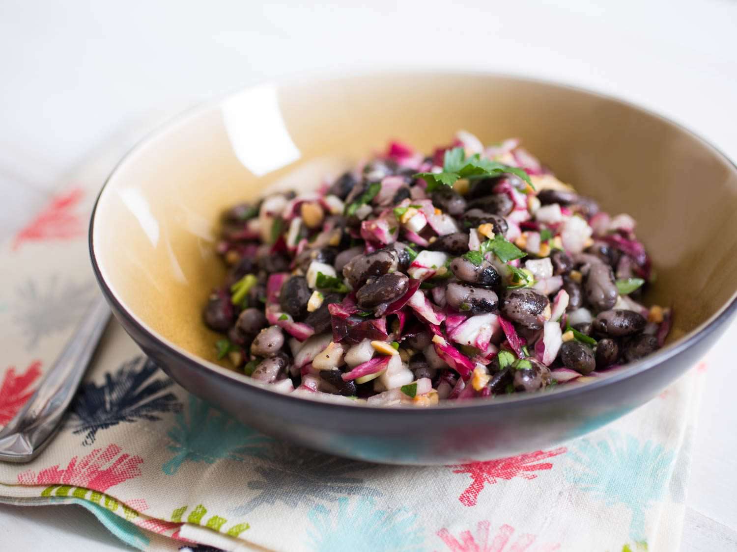 A ceramic bowl of Bean Salad With Radicchio, Radish, Pickled Onions, and Marcona Almonds
