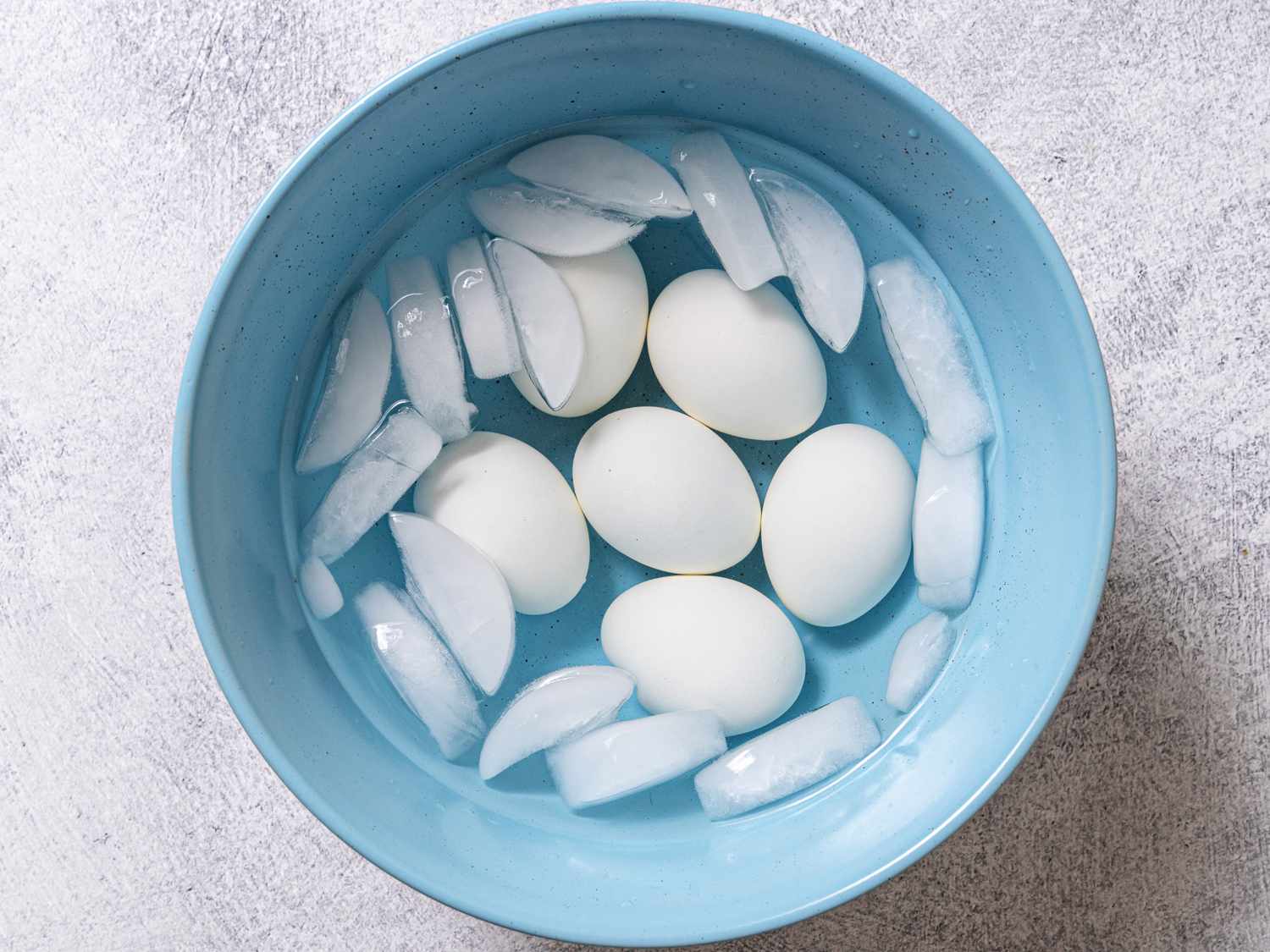 The steamed eggs placed in the blue bowl containing the ice bath.
