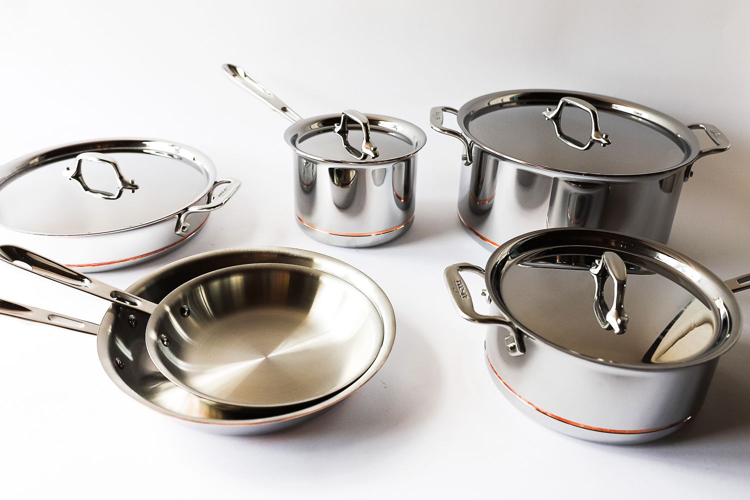 A cookware set consisting of pots pans and lids arranged on a surface