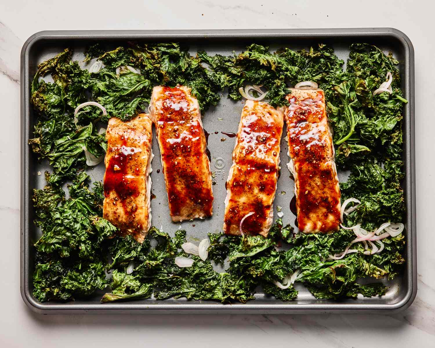 Tray of pomegranateglazed salmon fillets with kale