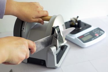 a person using a knife sharpener to sharpen a chef's knife