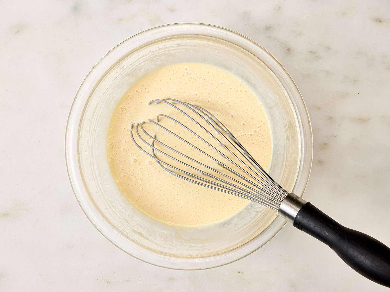 Batter in a glass bowl with a whisk resting on the side