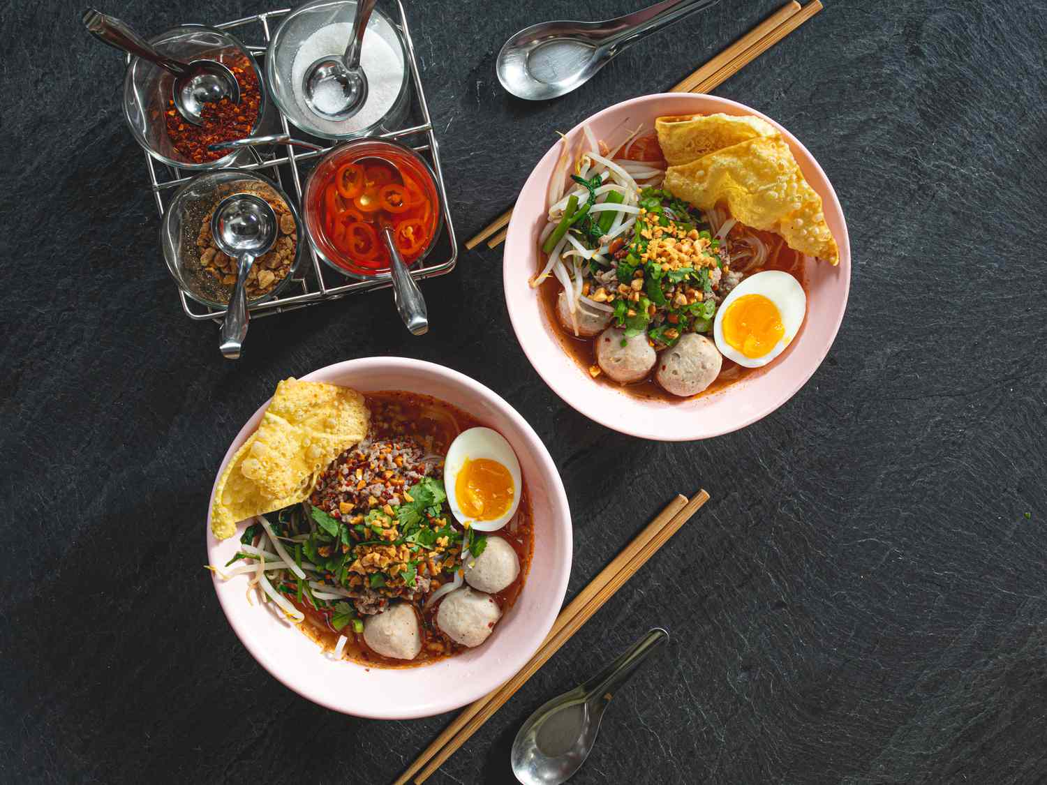 Overhead view of two bowls of Guaydtiaao Tom Yam Moo Saap