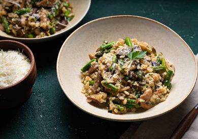 Mushroom and asparagus risotto plated in a shallow dish.
