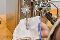 A hand using a cloth to wipe part of the Lelit MaraX Espresso Machine PL62X-120
