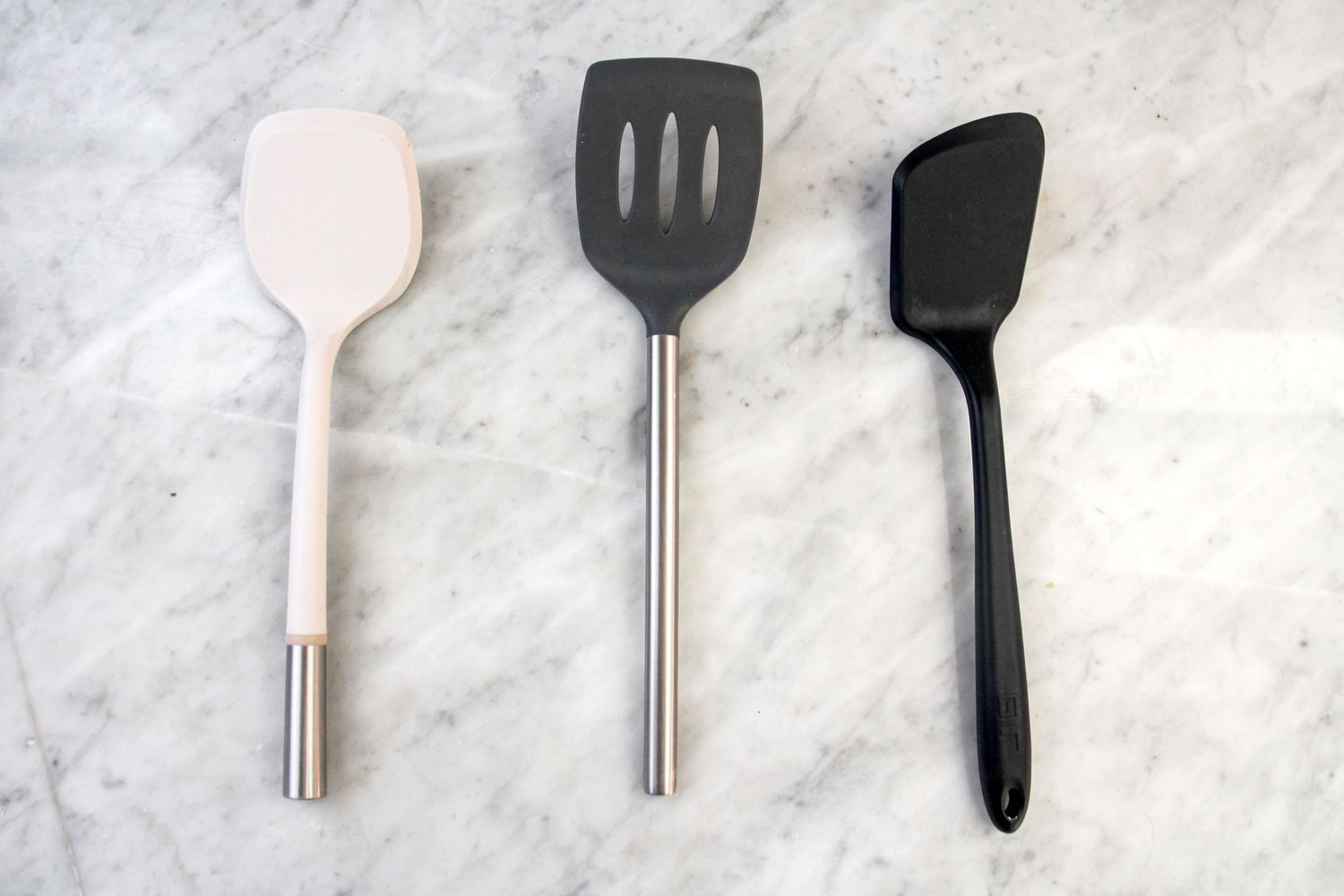 A collection of three silicone offset spatulas on a marble surface.