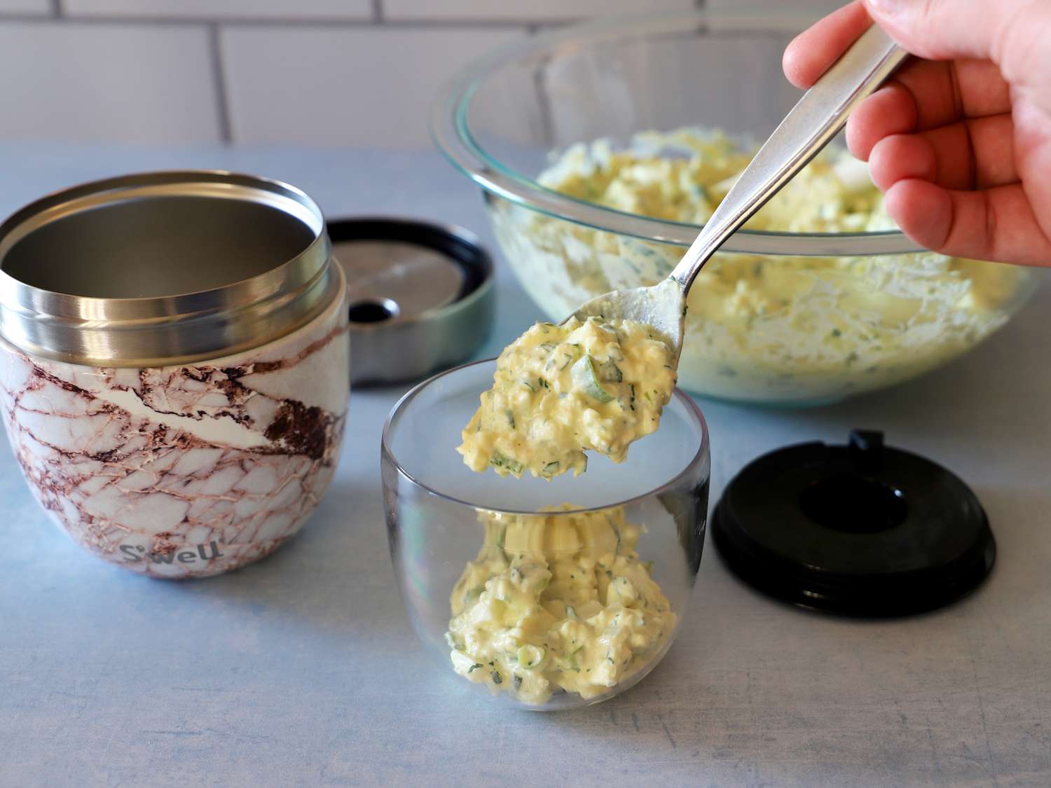 a person scooping egg salad into the removeable jar in the swell thermos