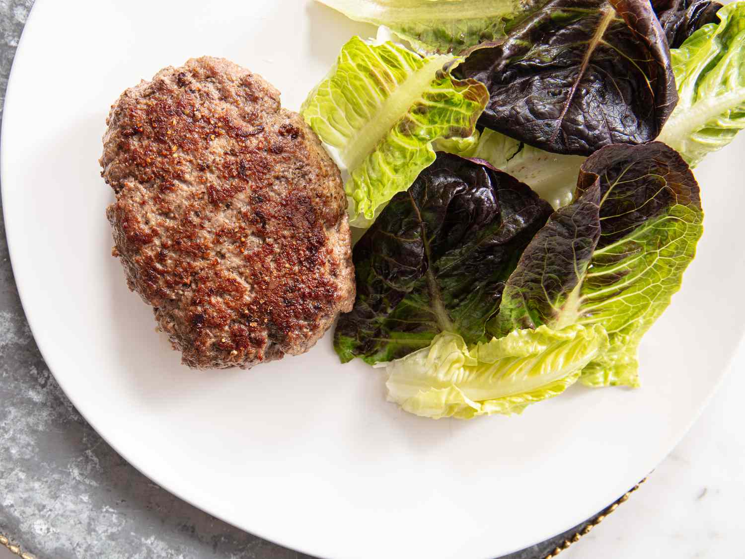 Hache Steak on a white plate with greens on the side 