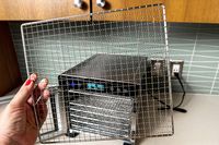 A person holding a stainless steel food dehydrator tray