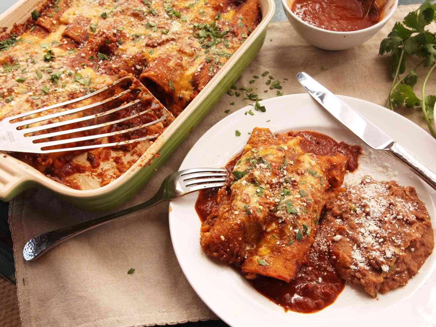Easy pressure cooker chicken enchiladas, served from the baking dish wit a fish spatula.