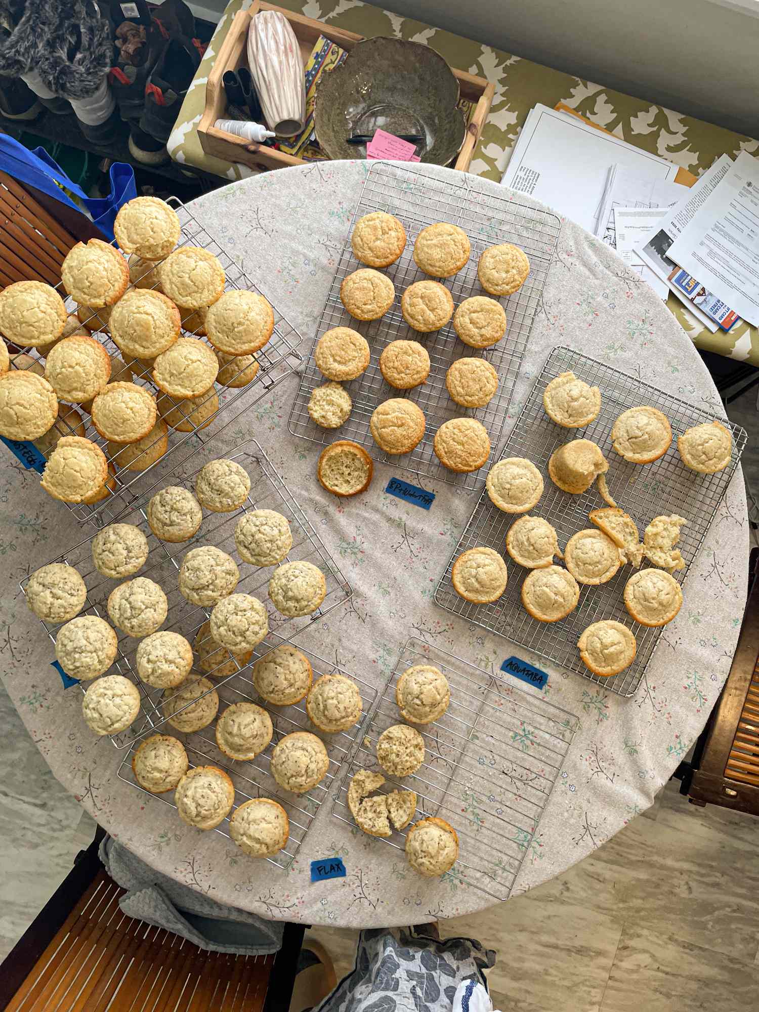 Multiple cooling racks placed on a round table each holding several muffins