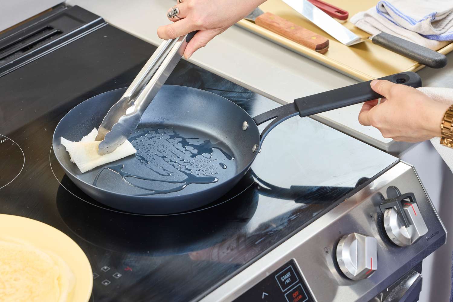 A person adds oil to the bottom of the OXO Obsidian 10 Inch Pre-Seasoned Carbon Steel Frying Pan