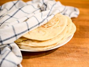 dish towel partially covering stack of soft, chewy flour tortillas