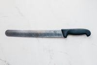 The Victorinox Fibrox Pro Slicing Knife laying on a marbled surface