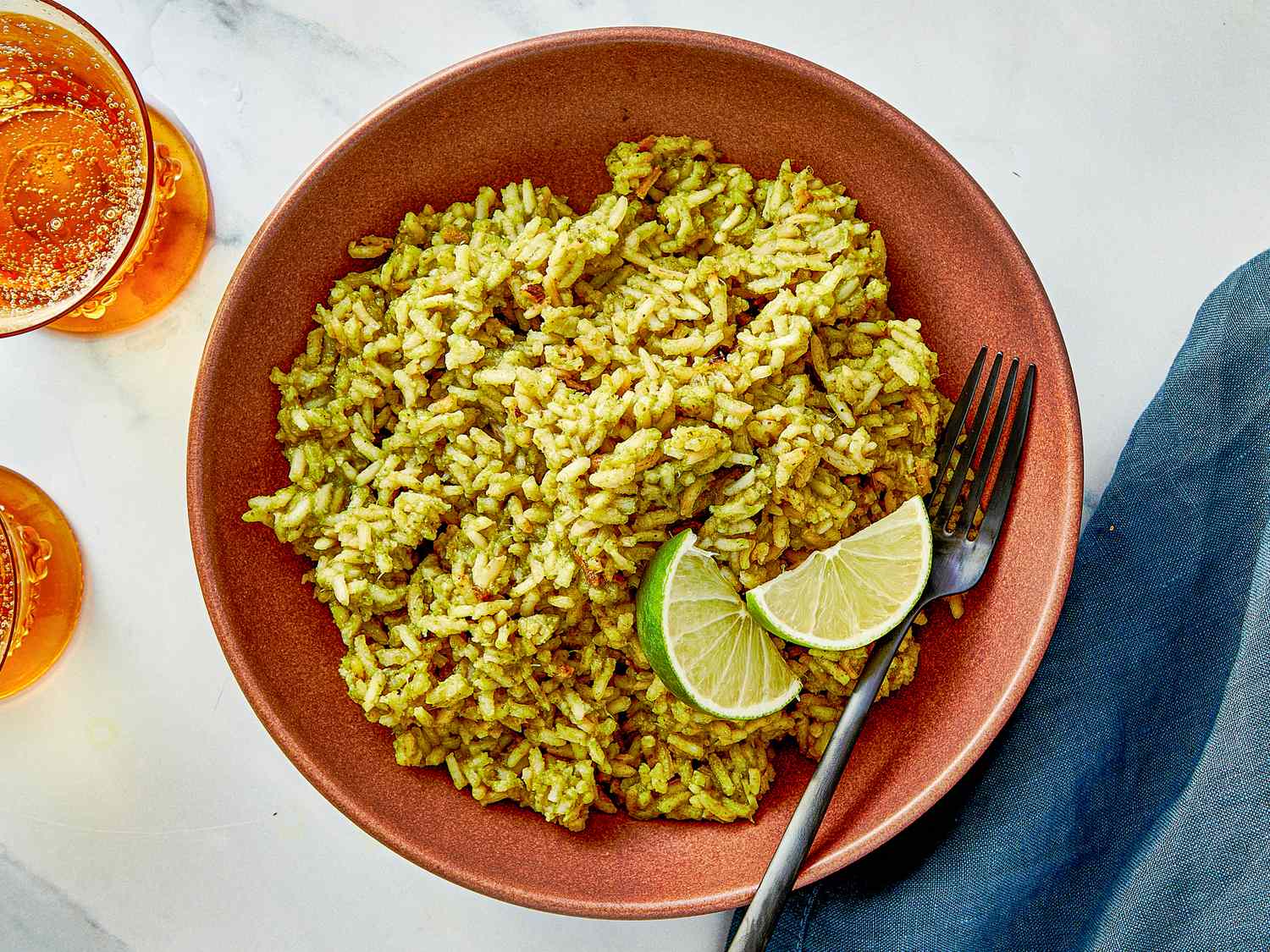 Bowl of rice with green seasoning garnished with lime wedges