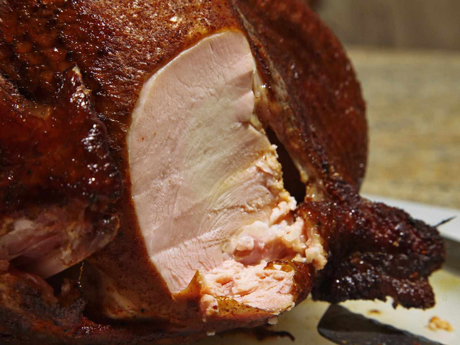 A slice has been carved from the smoked turkey's breast to reveal a moist-looking interior.