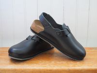 Black Birkenstock clogs on a wooden countertop.