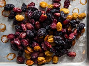 A medley of oven-dried purple, green, and red grapes piled on a sheet pan.