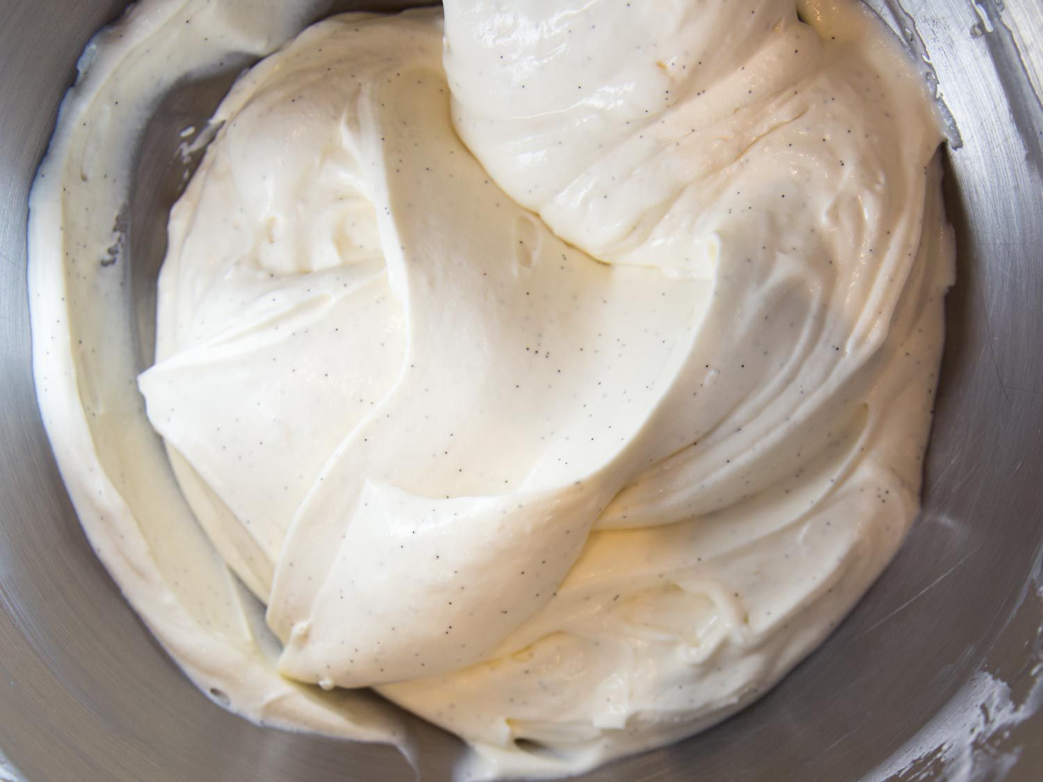 Whipped Greek yogurt flecked with vanilla seeds, in a metal bowl.