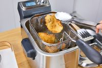A person fries food in the Breville BDF500XL Smart Fryer