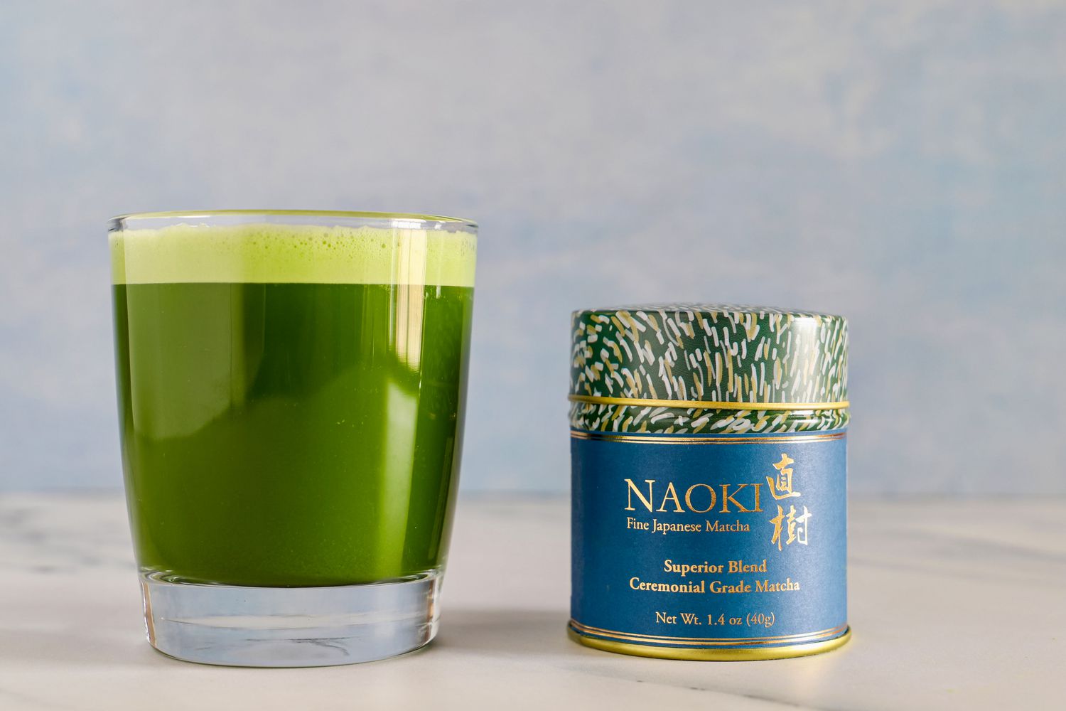 A glass of Naoki Matcha Superior Ceremonial Blend next to the container