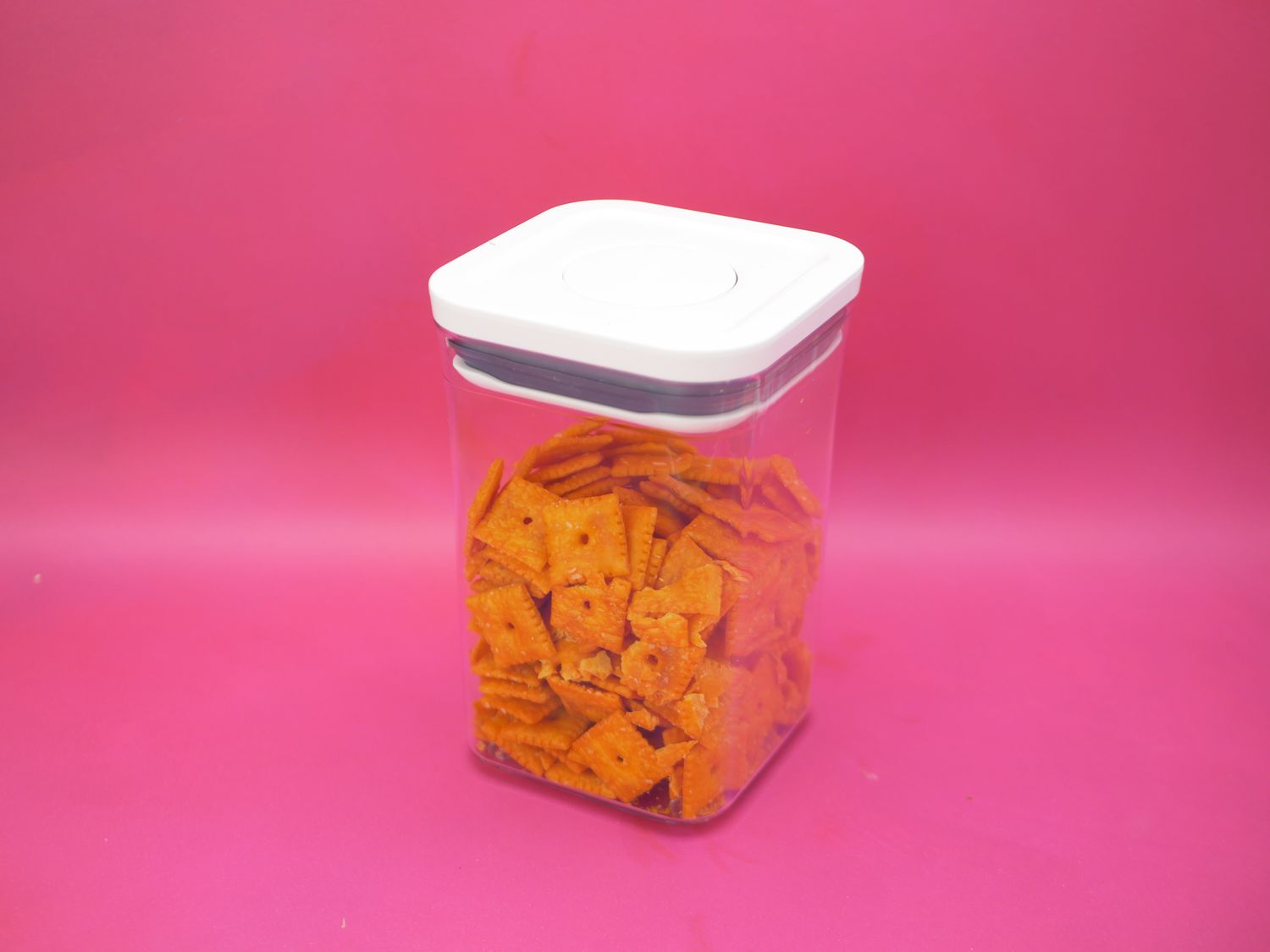 OXO container filled with cheez its on pink background 