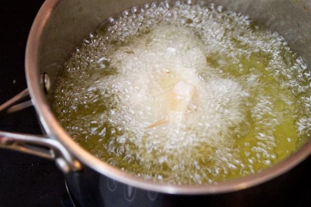 A saucepan of bubbling oil, with a chicken skin–wrapped matzo ball frying in it