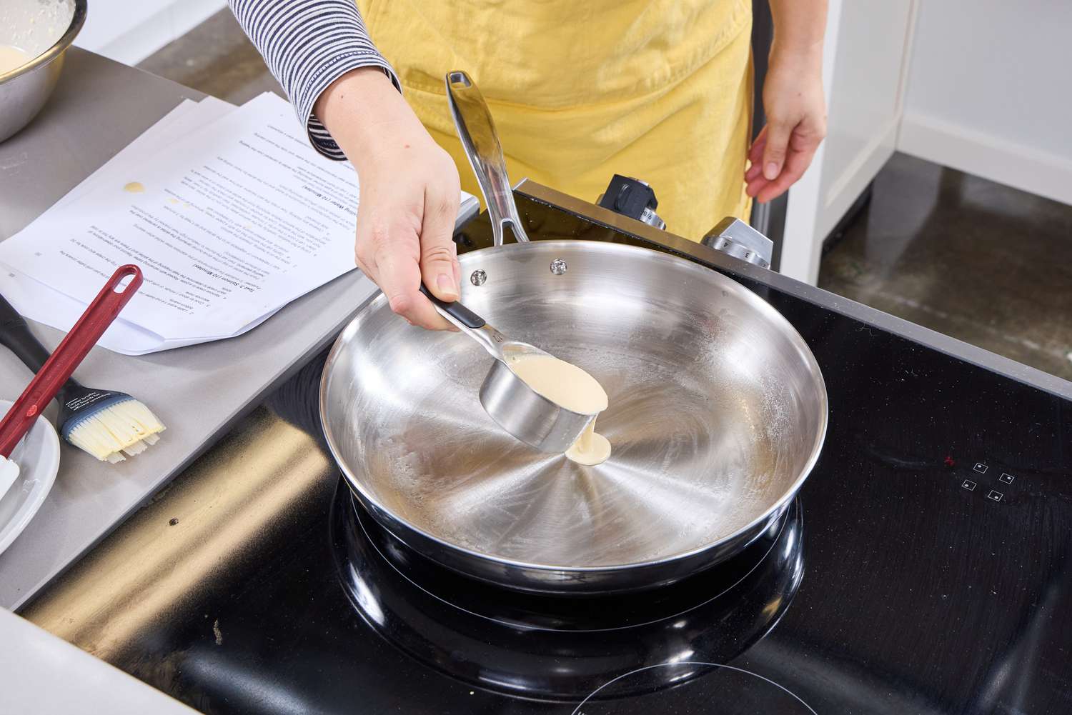 A person pours crepe batter into the Tramontina 12-Inch Stainless Steel Skillet