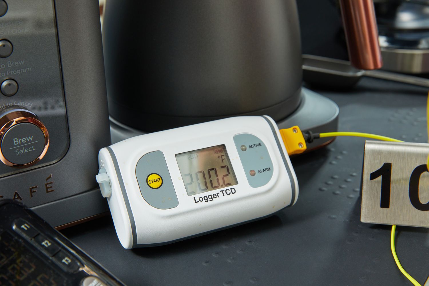 A thermometer's display reading 200.2˚F next to a coffee maker.