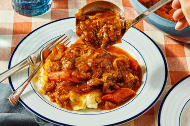 Plate of Swiss steak with mashed potatoes and a serving spoon midaction