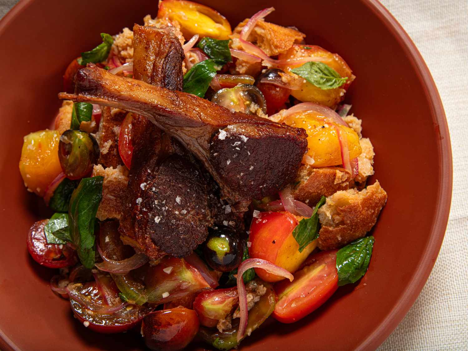 Warm panzanella salad with bread tomatoes and greens in a bowl