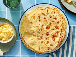 A plate of lefse flatbreads with butter on the side set on a tiled surface