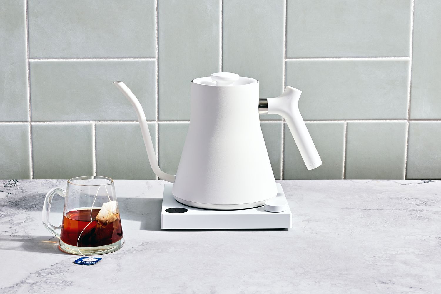 Fellow Stagg EKG Electric Pour-Over Kettle displayed on a marble counter with a mug of tea