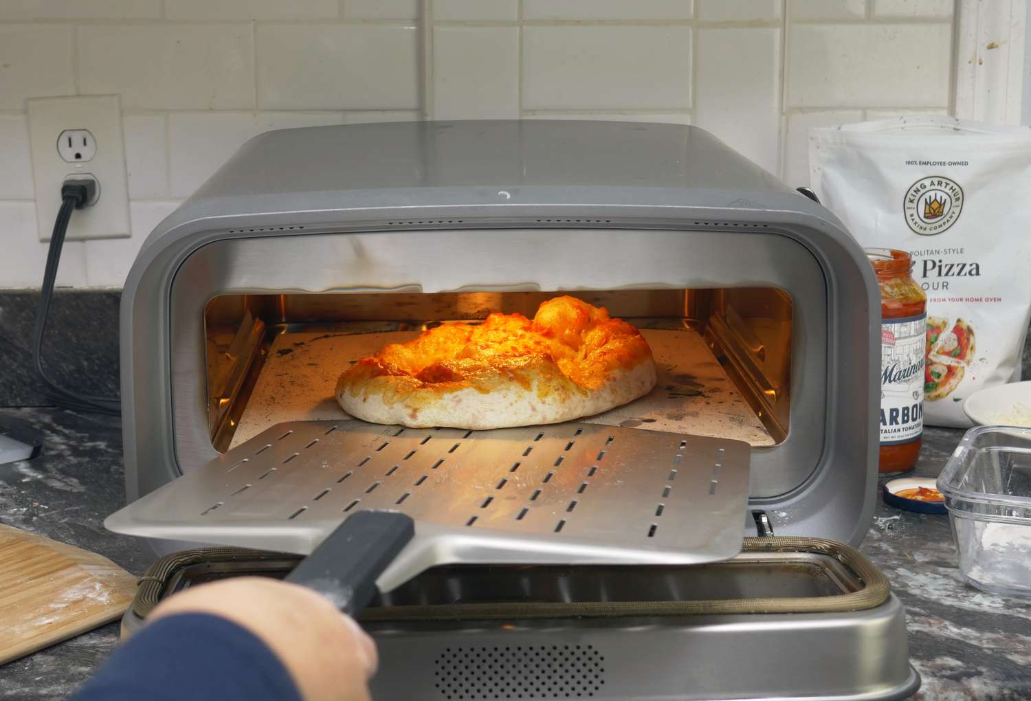 a person turning a pizza in an indoor pizza oven